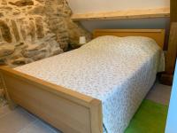 a bed in a room with a stone wall at Gîte chez le Gaulois in Carsac-Aillac