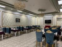 een eetkamer met tafels en stoelen en een kroonluchter bij HOTEL ALMAZ PLAZA in Yakkasaray