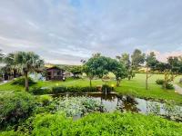 a garden with a pond and trees and a house at Kenting Summerland Garden Resort in Eluan