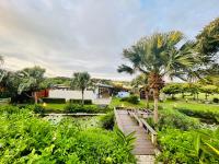 a wooden walkway leading to a house with palm trees at Kenting Summerland Garden Resort in Eluan