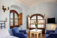 a living room with two blue chairs and a tv at Hotel Tugasa Castillo de Castellar in Castellar de la Frontera