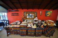 een tafel met eten erop, met een vrouw die erachter staat bij Hosteria Casa Giralda in Baños