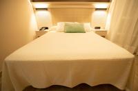 a large white bed with a green pillow on it at Hotel Diufain in Conil de la Frontera