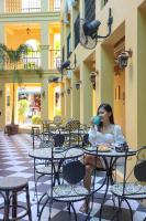una mujer sentada en una mesa bebiendo una taza de café en The Quba Boutique Hotel Pattaya, en Pattaya central