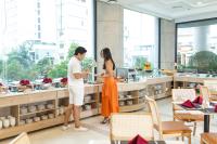 Un hombre y una mujer de pie en un mostrador de un restaurante. en Odin Hotel Quy Nhon, en Quy Nhon