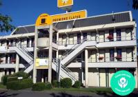 a large white building with a yellow sign on it at Premiere Classe Cambrai Proville in Cambrai