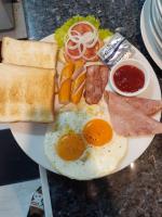 een bord ontbijtproducten met eieren, vlees en toast bij Phratamnak Inn guesthouse - 100 mtr from the beach in Pattaya South