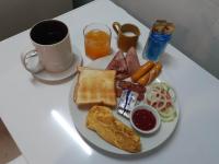 een bord ontbijtproducten op een tafel met een kopje koffie bij Phratamnak Inn guesthouse - 100 mtr from the beach in Pattaya South