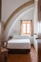 a bedroom with a white bed in an attic at Hotel Tugasa Convento San Francisco in Vejer de la Frontera