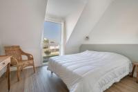 a white bedroom with a bed and a desk and a window at Lumineuse et accueillante maison pour 8 personnes in Sarzeau