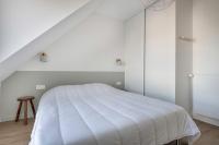 a white bedroom with a white bed and a stool at Lumineuse et accueillante maison pour 8 personnes in Sarzeau