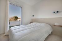 a white bed in a white bedroom with a large window at Lumineuse et accueillante maison pour 8 personnes in Sarzeau