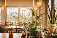 a room with potted plants and tables and a window at The Farmhouse at Redcoats in Stevenage