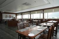 Un comedor con mesas y sillas y ventanas. en HOTEL SUNRISE HOSPITALITY, en Vijayawāda