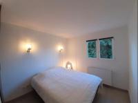 a white bedroom with a bed and two windows at Hossegor city in Soorts-Hossegor