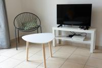 a living room with a tv and a chair and a table at 2 pièces Port Cabourg - 2 à 4 personnes - 34 m2 - Balcon - Vue Port - Nouveau sur Booking ! in Dives-sur-Mer