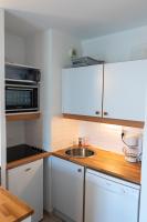 a kitchen with white cabinets and a sink and a microwave at 2 pièces Port Cabourg - 2 à 4 personnes - 34 m2 - Balcon - Vue Port - Nouveau sur Booking ! in Dives-sur-Mer