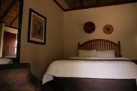 a bedroom with a large bed with white sheets at Manong Game Lodge in Gaborone