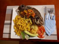 Un plato de comida con patatas fritas y un pescado. en Kasenene Legacy Hotel, en Fort Portal
