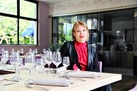 * La Maisonette * avec Sauna & Hammam privatifs في نيفير: امرأة تجلس على طاولة مع كؤوس النبيذ