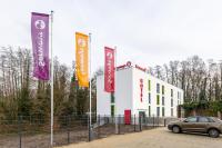 ラーティンゲンにあるSerways Hotel Höselの旗のある建物の前に停車する車