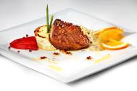 un piatto bianco con un pezzo di carne e fette d'arancia di HCC St. Moritz a Barcellona