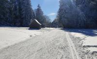 a snow covered road with a building in the distance at Bulle de Bois, écolodge insolite avec spa privatif au milieu des volcans - Bulles d&#39;Herbe in Queyrières