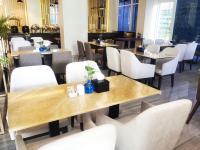 Un comedor con mesas y sillas blancas. en Surabaya River View Hotel, en Surabaya