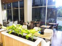 Un restaurante con mesas, sillas y ventanas. en Surabaya River View Hotel, en Surabaya