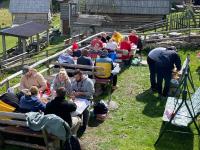 a group of people sitting at tables in the grass at Zlatna koliba Namir Zuka in Fojnica