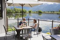 Ein Mann und eine Frau sitzen mit einem Hund an einem Tisch. in der Unterkunft Ninepipes Lodge in Polson