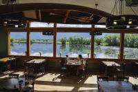 Menschen sitzen an einem Tisch in einem Restaurant mit Blick auf einen Fluss in der Unterkunft Ninepipes Lodge in Polson