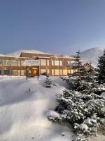 a building covered in snow with trees in front of it at The View in Honningsvåg