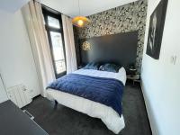 a bedroom with a bed with a blue comforter at Joli appartement hyper-centre in Alençon