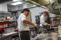 twee mannen in een keuken die eten klaarmaken in een keuken bij Gasthaus Johanning eK in Uslar