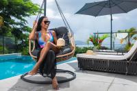 a woman sitting in a swinging chair next to a pool at Karibea Squash Hôtel in Fort-de-France