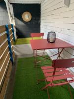 a red table and chairs on a porch with grass at 3)Maison tout confort boucle de la Seine in Duclair