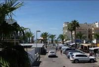 a street with parked cars and palm trees and buildings at 100 m de la plage - Les Cigales de Mer - Studio Cabine - Parking in Le Grau-du-Roi