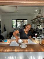 a woman standing behind a counter with a cup of coffee at Neighbourgood Hill in Cape Town
