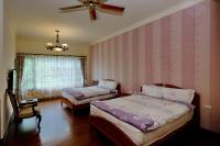a bedroom with two beds and a ceiling fan at Qixingtan Hai Wan B&amp;B in Dahan