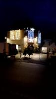 una vaca parada frente a un edificio con luces de Navidad en Bienvenue, en Saint-Pierre-de-Plesguen