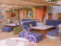 a room with blue chairs and tables and paintings on the wall at Auberge Triskell in Nouakchott
