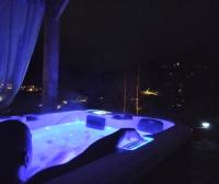 a man sitting in a jacuzzi tub at night at Au chalet de JO in Muhlbach-sur-Munster