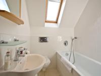 a white bathroom with a sink and a toilet at Quay House, Porth Beach in Saint Columb Minor