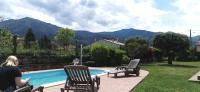 a woman sitting in chairs next to a swimming pool at Chambres d&#39;hôtes et gîtes Al Pati in Sorède