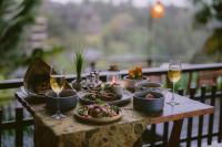 een tafel met borden met eten en glazen wijn bij Adiwana Svarga Loka - A Retreat Resort in Ubud