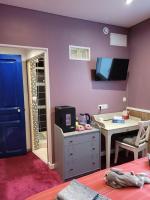 a room with a purple wall with a desk and a tv at Le Relais De L&#39;Aube in Villers-Bretonneux