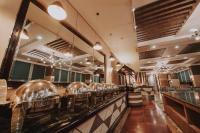 a restaurant with a bar with a row of dishes at Kingwood Hotel Sibu in Sibu