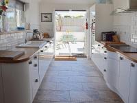 a kitchen with white cabinets and a tile floor at Bowji in St. Just