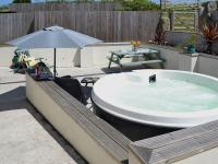 a hot tub sitting on a patio with an umbrella at Bowji in St. Just